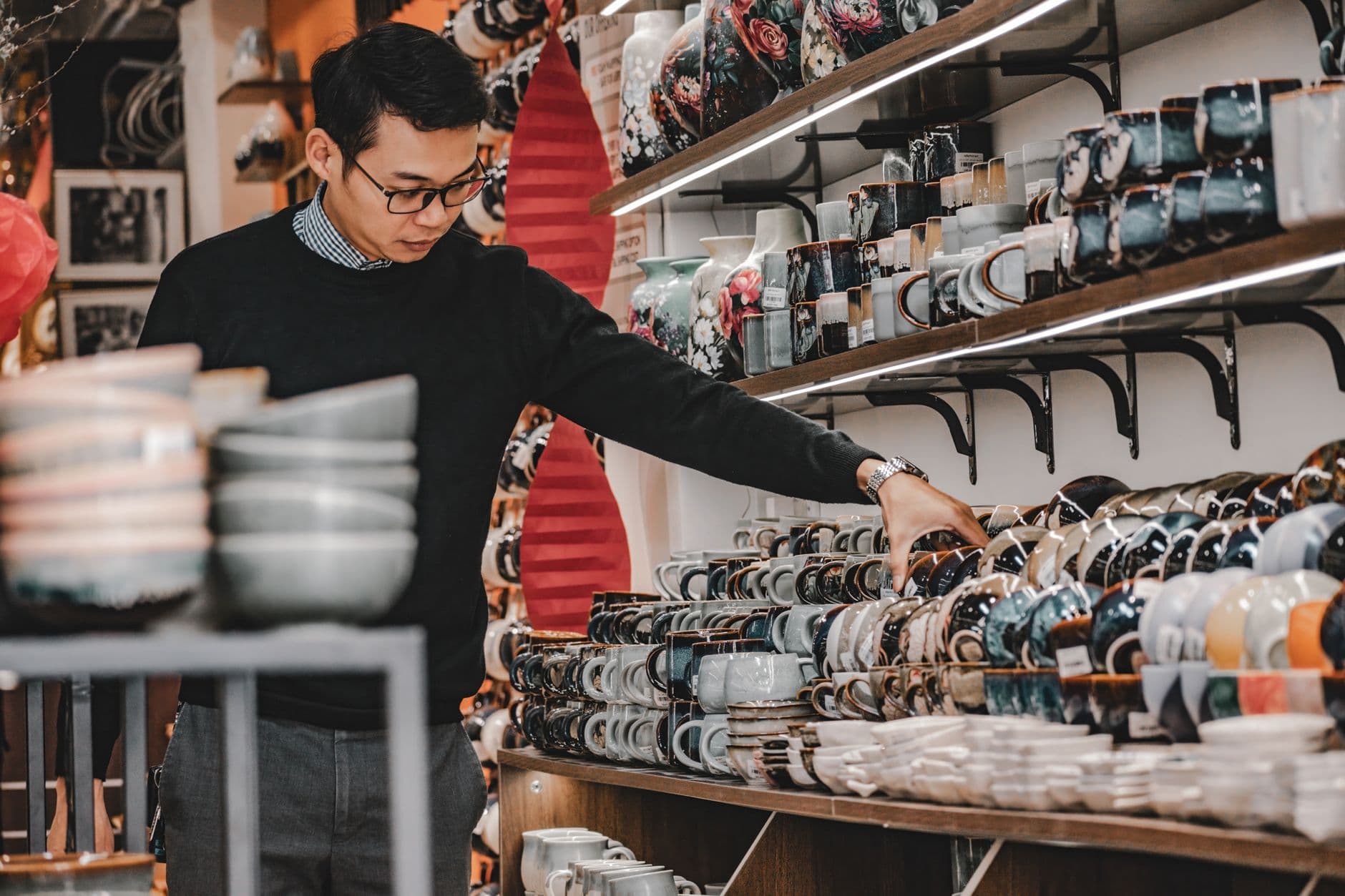 A shopper browsing densely stocked shelves of housewares inside a variety store