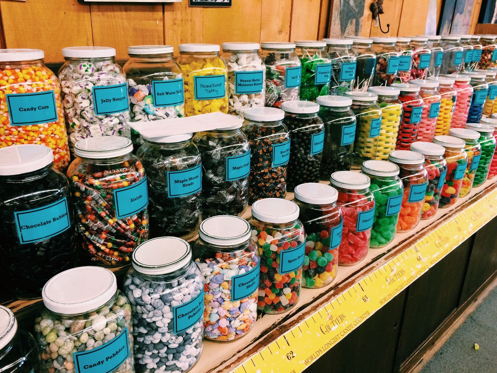 A long wall of glass jars filled with assorted labeled candy